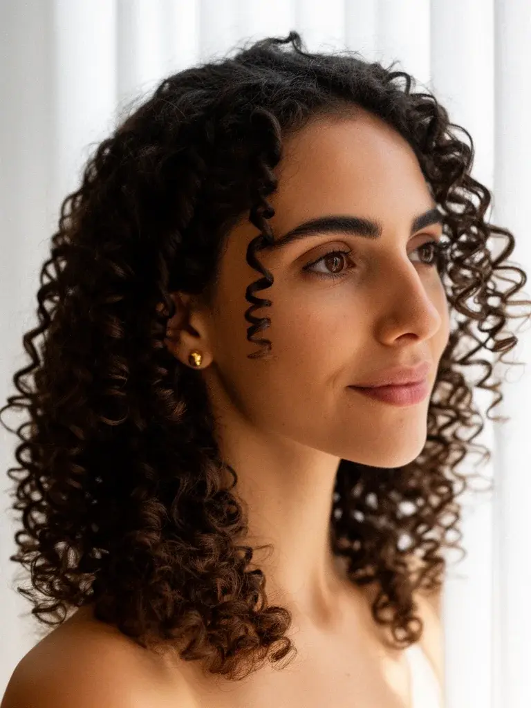 Shoulder-length spiral curls on a Brazilian woman with dark brown hair, natural light